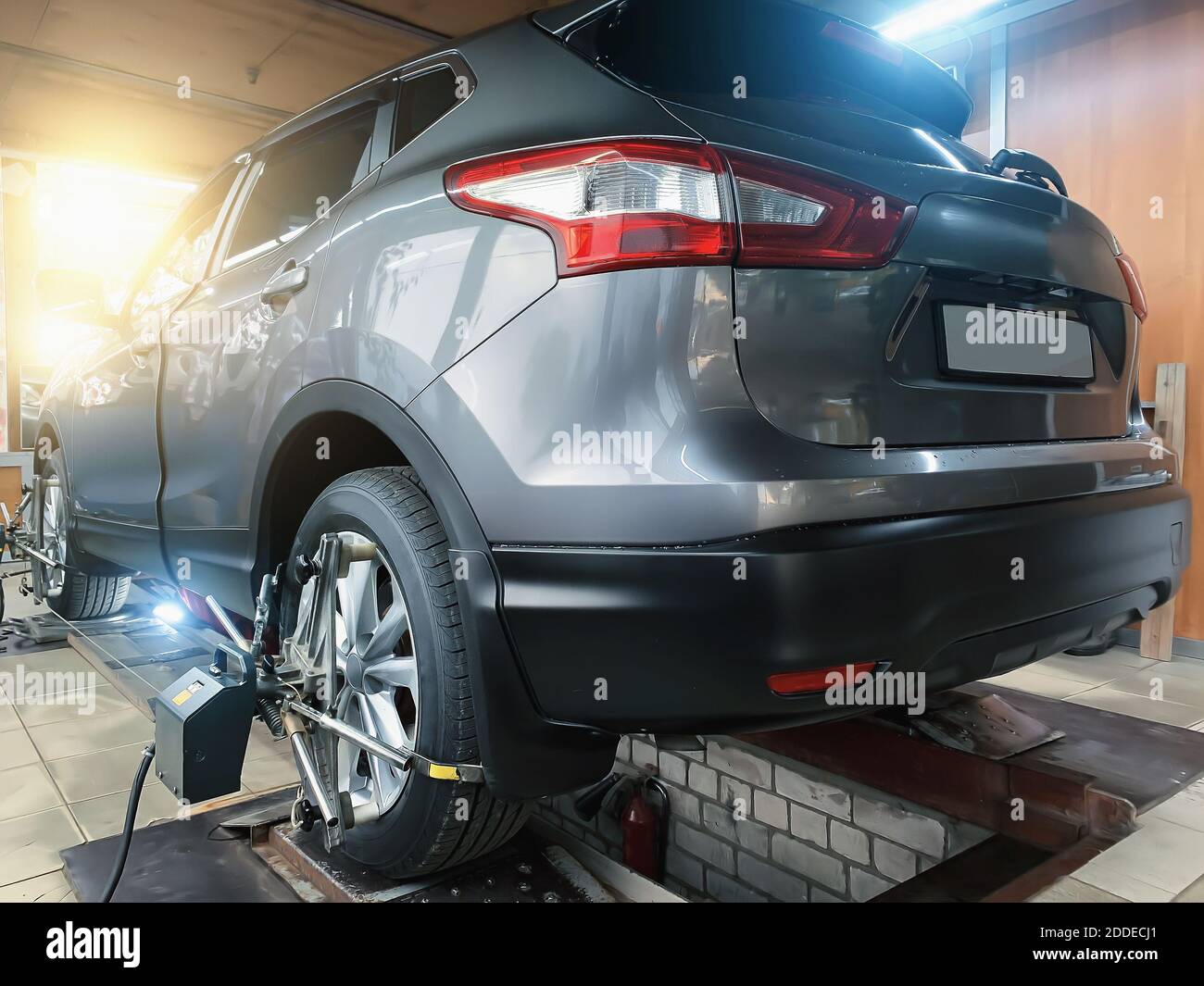 Car in auto service. Sensors on SUV wheels check alignment camber toe. Work with chassis and suspension of car. Stock Photo