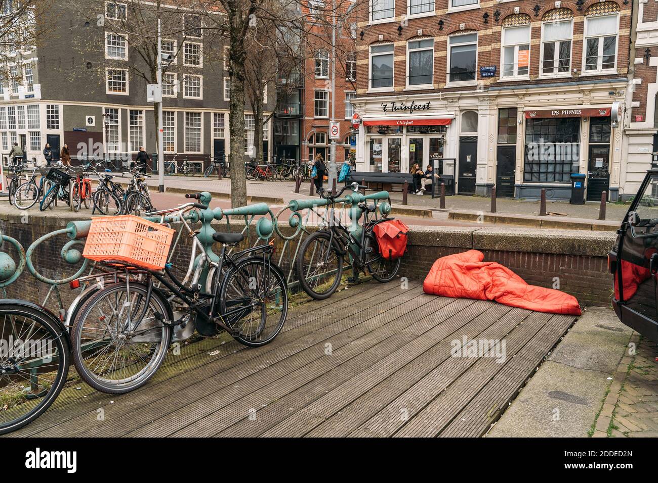 Amsterdam, Netherlands - March 2020 : Homeless man sleeps under red blanket in center of European city. Stock Photo