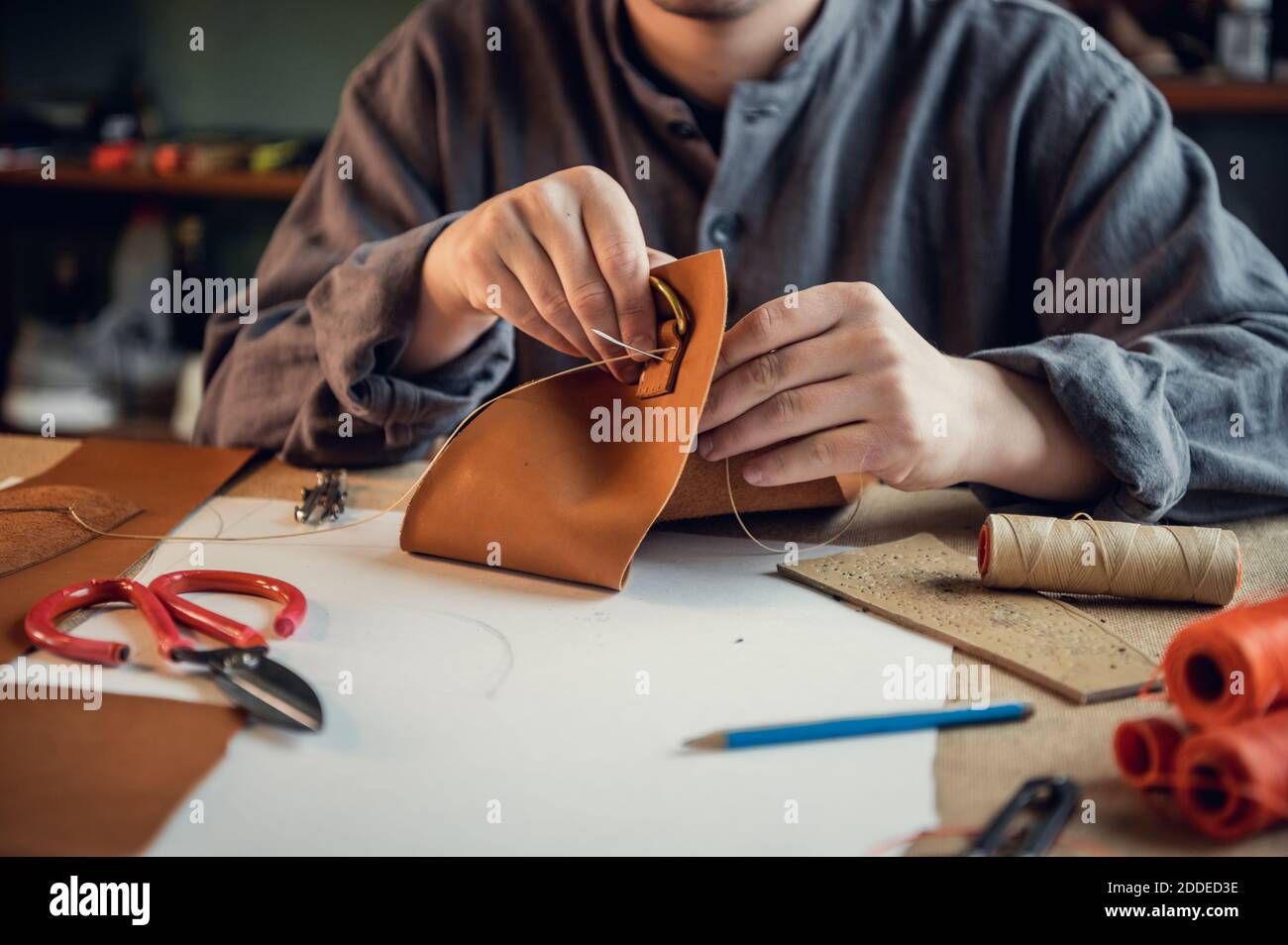 A young shoemaker manually sews decorative elements to leather shoes in the  workshop Stock Photo - Alamy