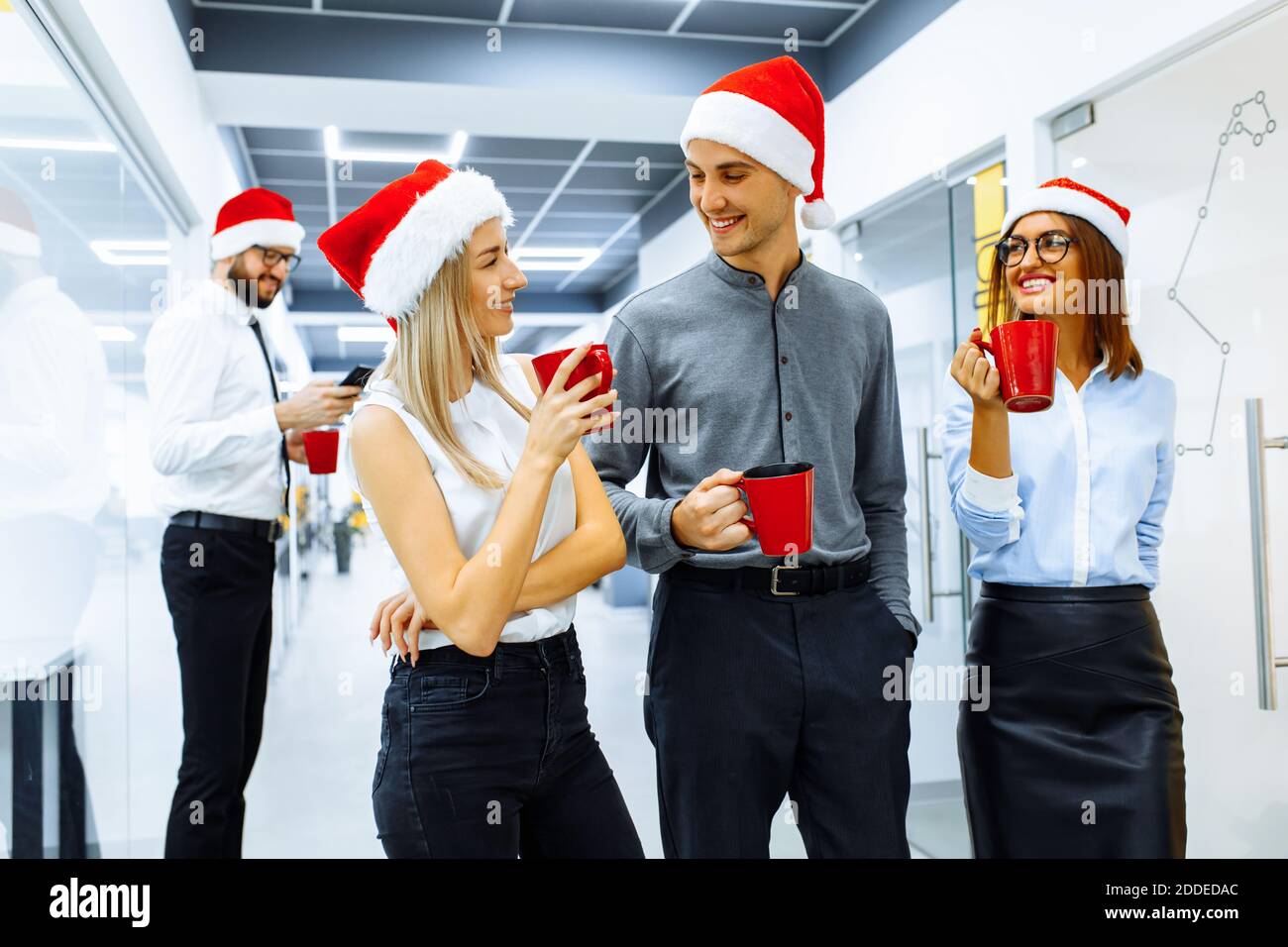 Group of happy business people wearing Santa Claus hats talking and ...