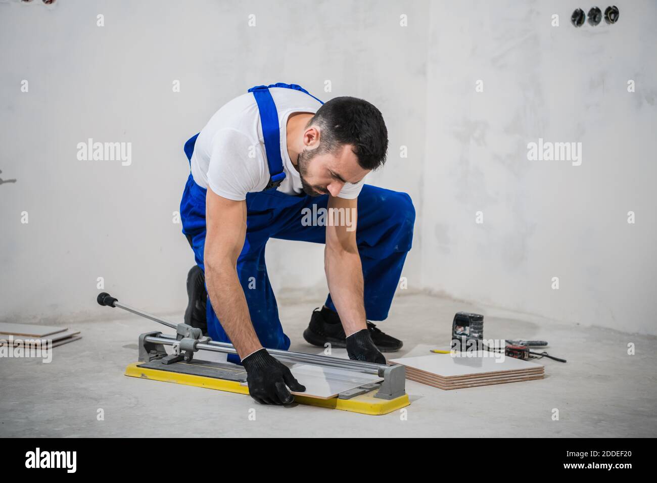 Young construction worker cuts tiles with a special tool Stock Photo