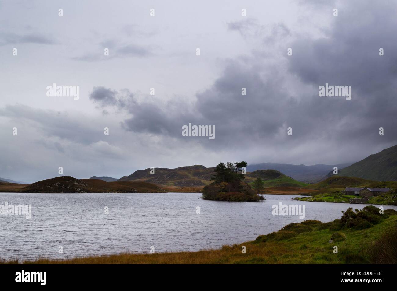 Autumn, Lake Cregennan in Gwynedd, Wales, with the hills behind in the clouds and some stone farm buildings Stock Photo