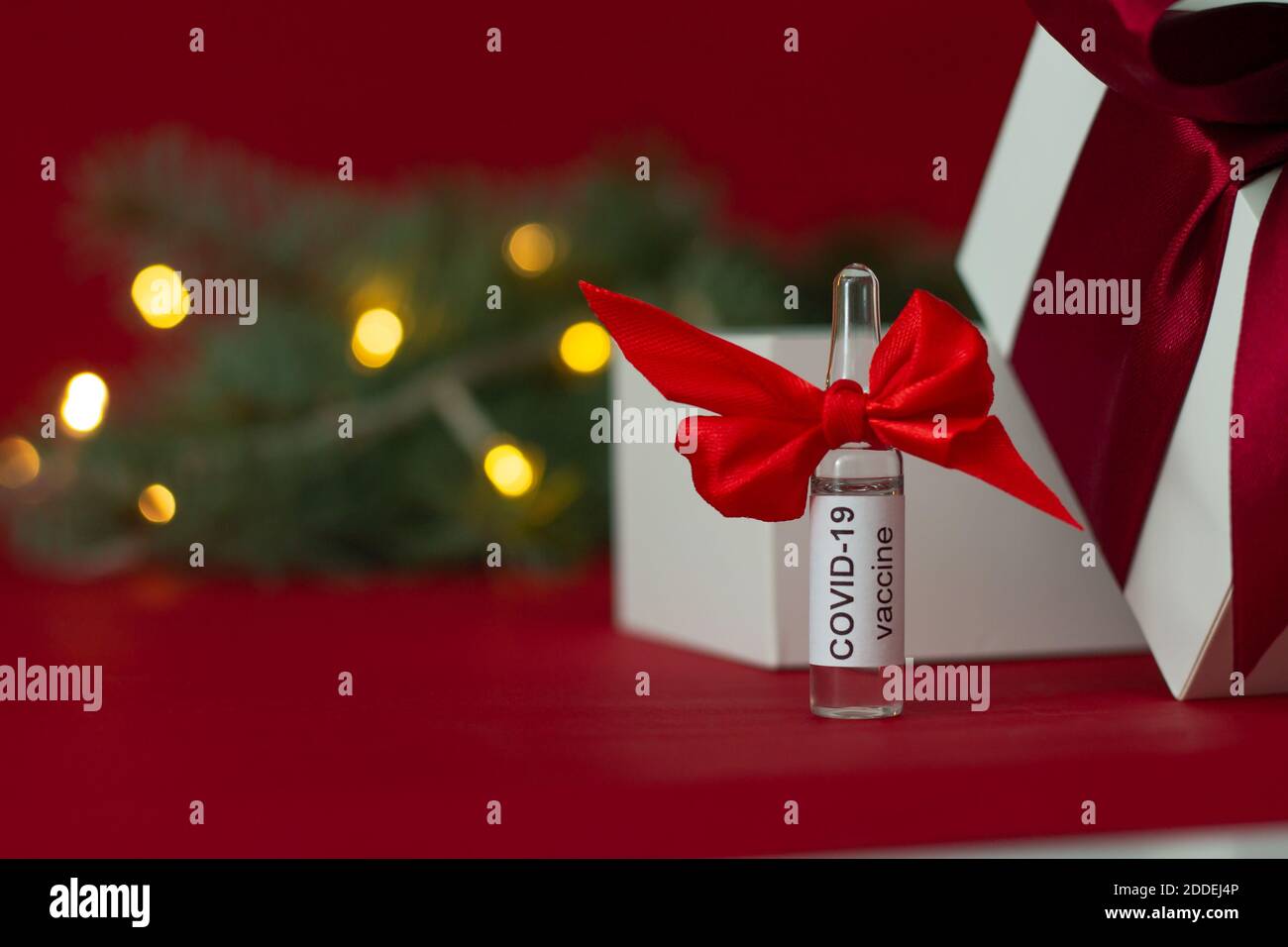 An ampoule of the COVID19 coronavirus vaccine stands as a gift near a Christmas tree branch