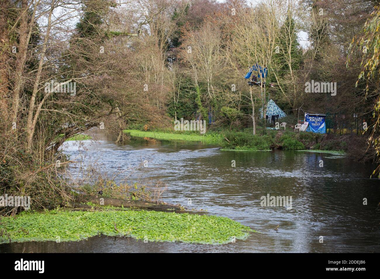 Denham, UK. 24th November, 2020. Denham Ford Protection Camp is pictured from a bridge over the river Colne in Denham Country Park. Activists based at Denham Ford Protection Camp on one side of the river Colne continue to oppose the rerouting of pylons through precious woodland and wetland in Denham Country Park for the controversial high-speed rail project which continues to have a hugely detrimental environmental impact in the Colne Valley. Credit: Mark Kerrison/Alamy Live News Stock Photo