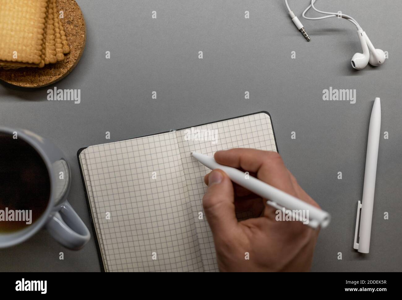 open notebook cup cookie and pens on grey table Stock Photo