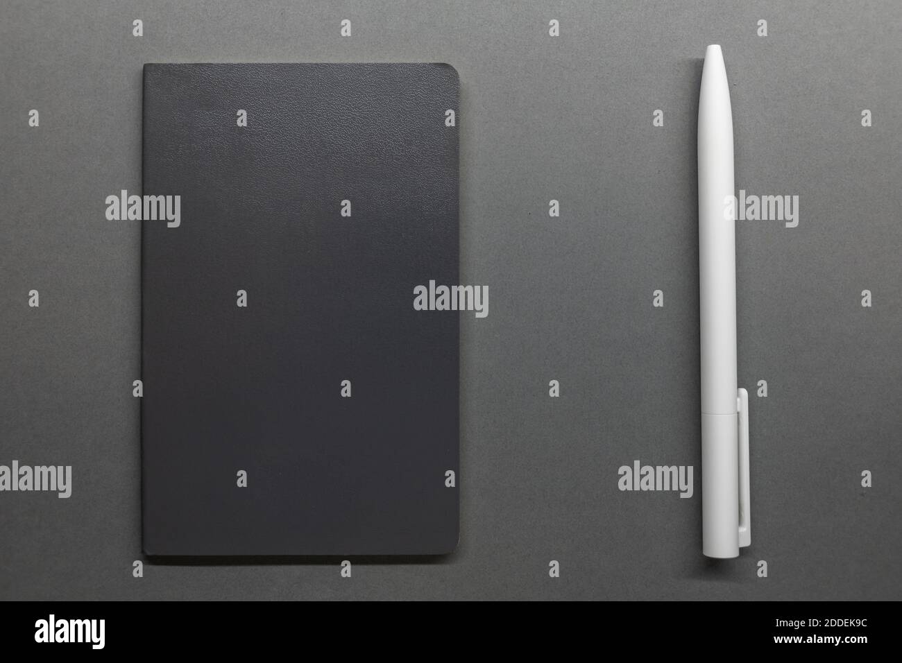 grey notebook and white pen on table flat lay Stock Photo