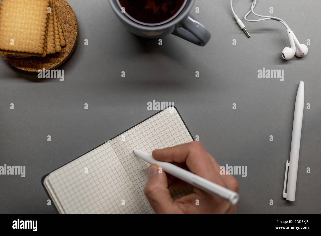 open notebook cup cookie and pens on grey table Stock Photo