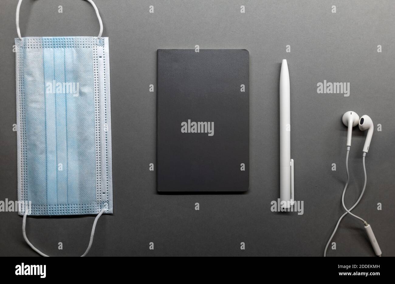 grey notebook face mask and white pen on table flat lay Stock Photo