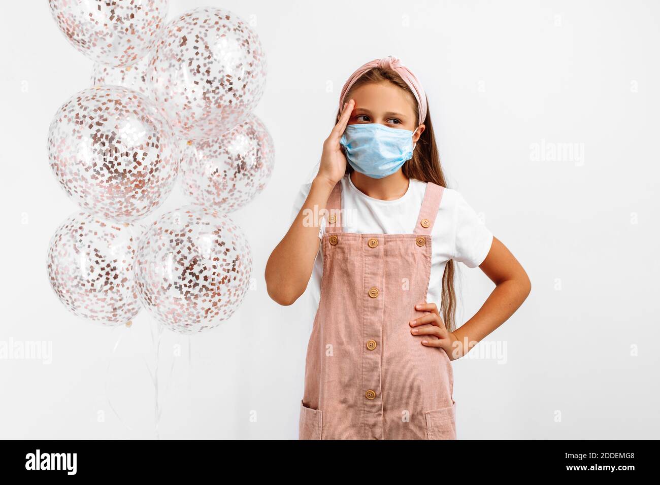 Pensive beautiful little girl in a medical protective mask on her face ...