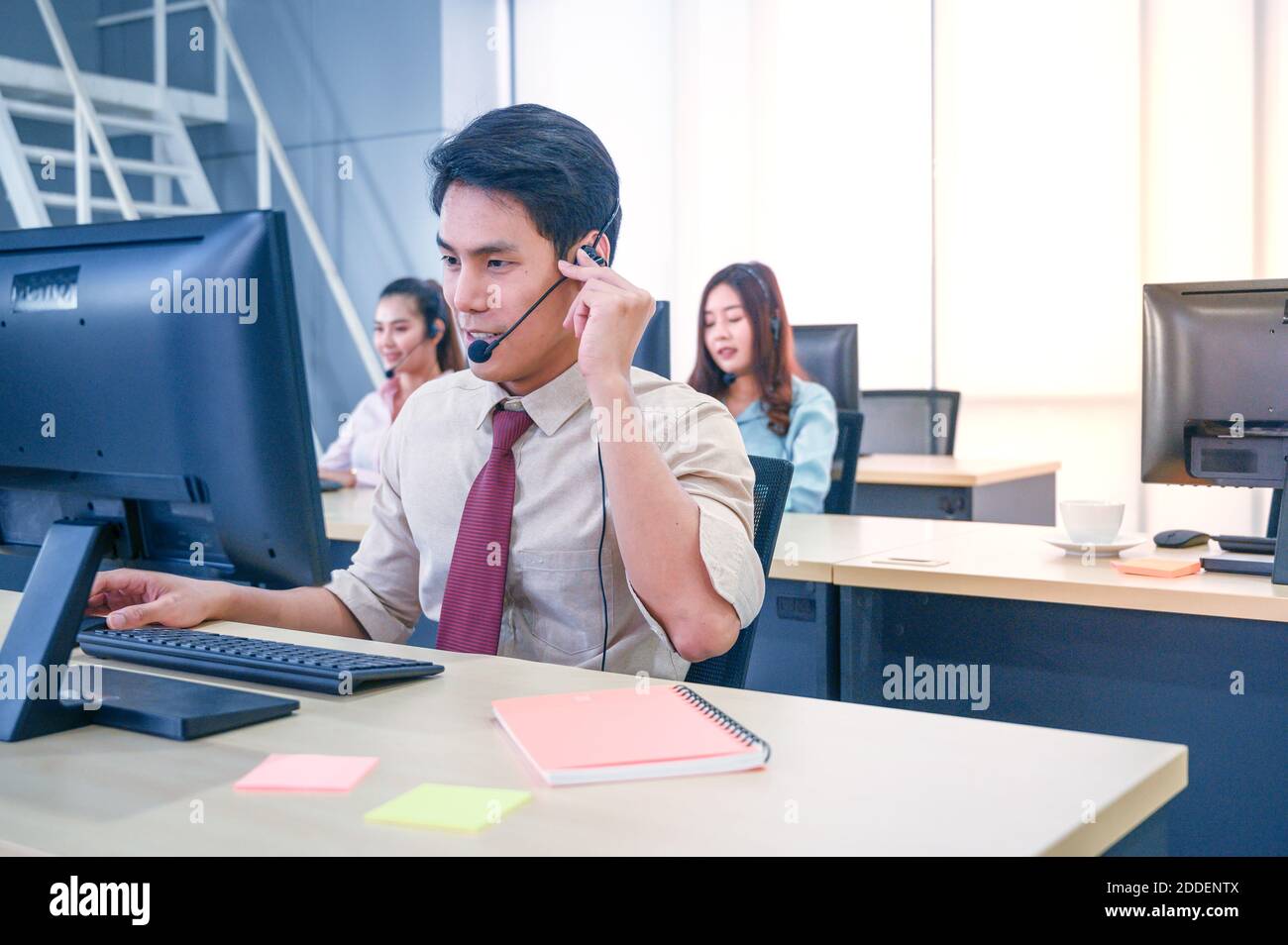 Young customer service men agent with headsets and computer working at office. Professional operator concept. Stock Photo