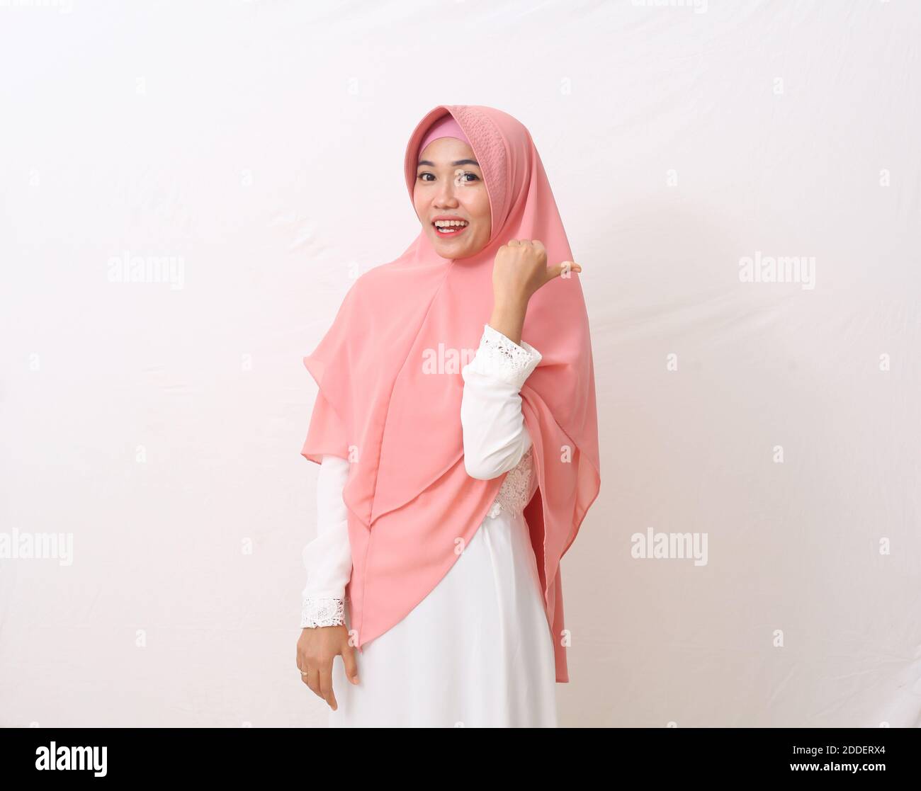 A portrait of happy asian muslim woman wearing a veil or hijab poiting ...