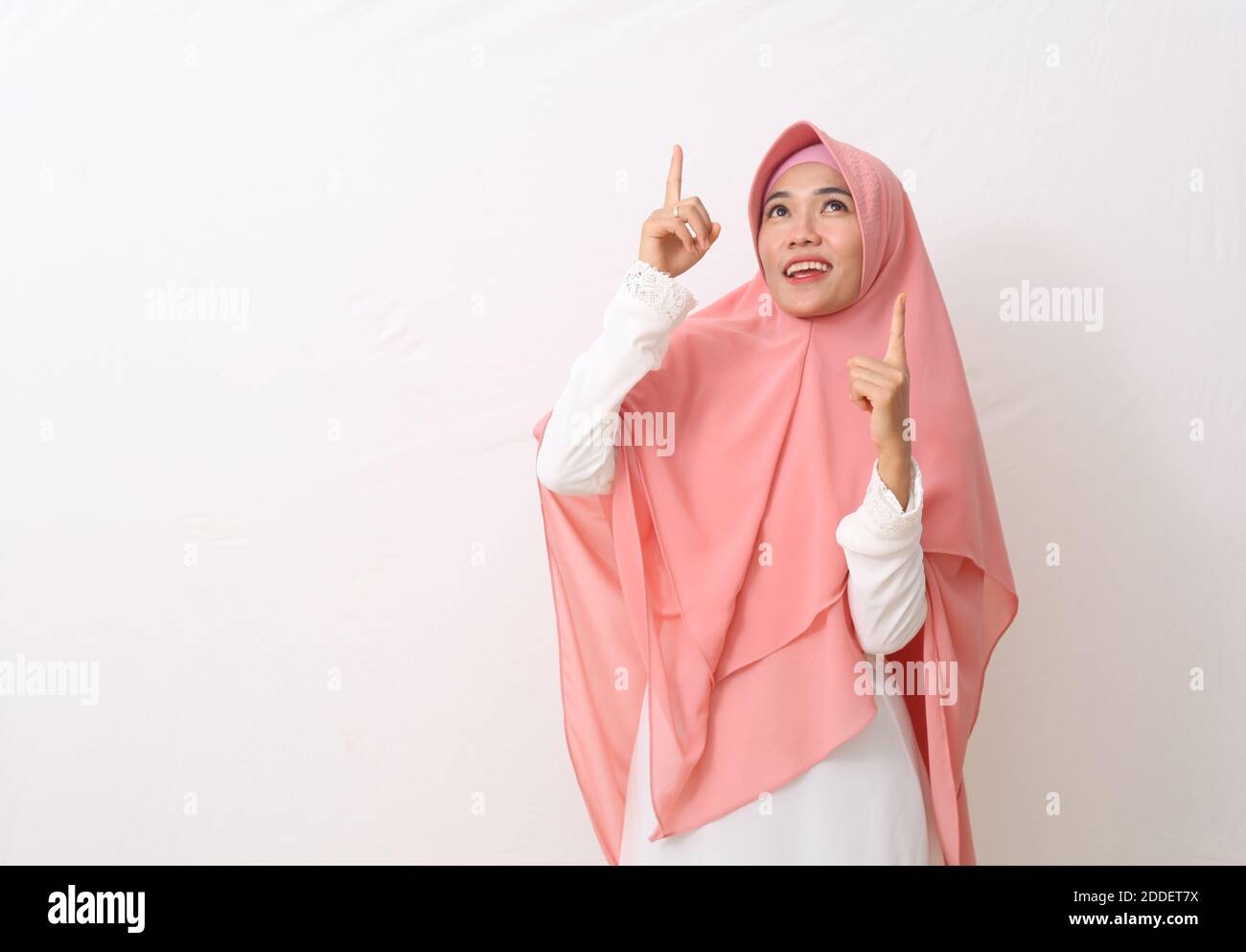 A portrait of happy asian muslim woman wearing a veil or hijab pointing ...