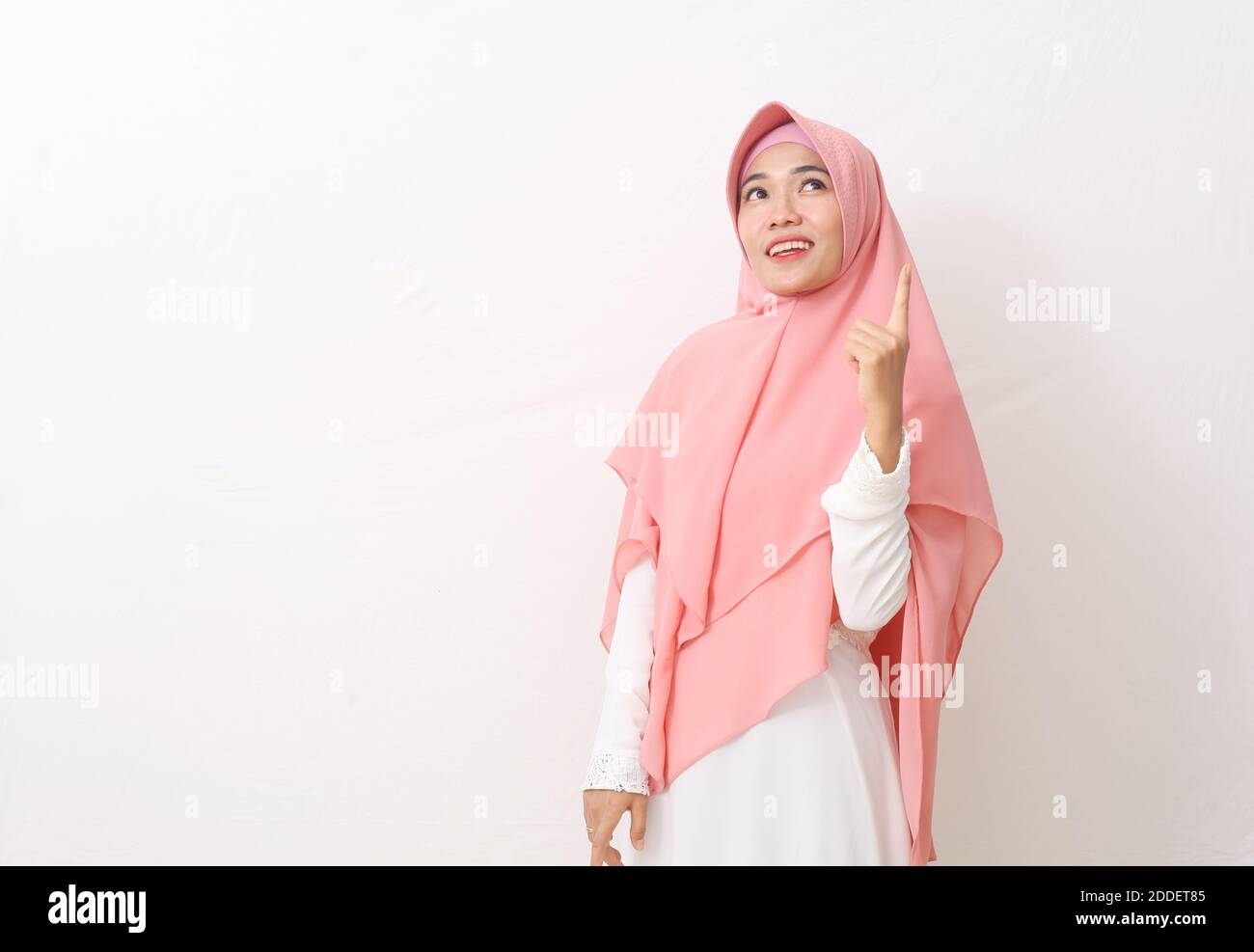 A portrait of happy asian muslim woman wearing a veil or hijab pointing ...