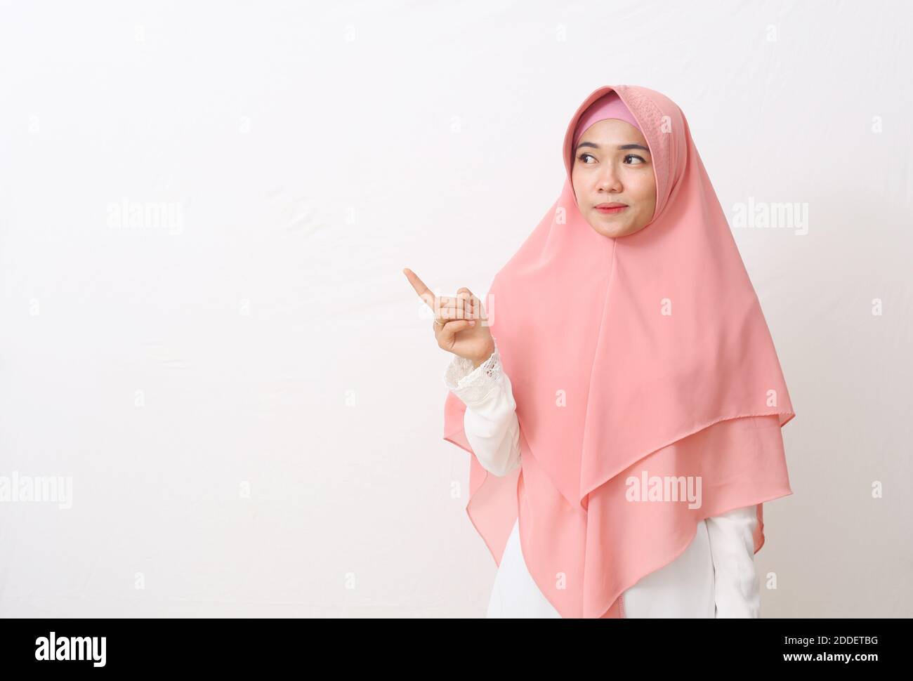 A portrait of happy asian muslim woman wearing a veil or hijab poiting ...
