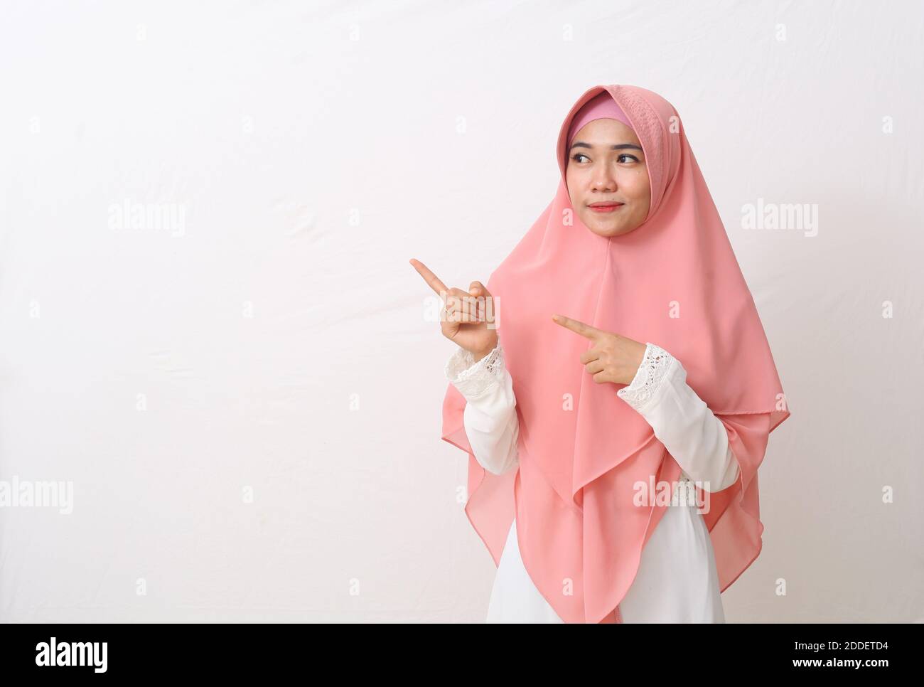 A portrait of happy asian muslim woman wearing a veil or hijab poiting ...