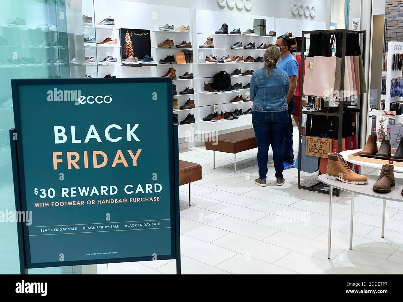 Orlando, United States. 24th Nov, 2020. A shopper wearing a face mask walks  past a Black Friday sale sign in a store at The Mall at Millenia as  merchants prepare for one