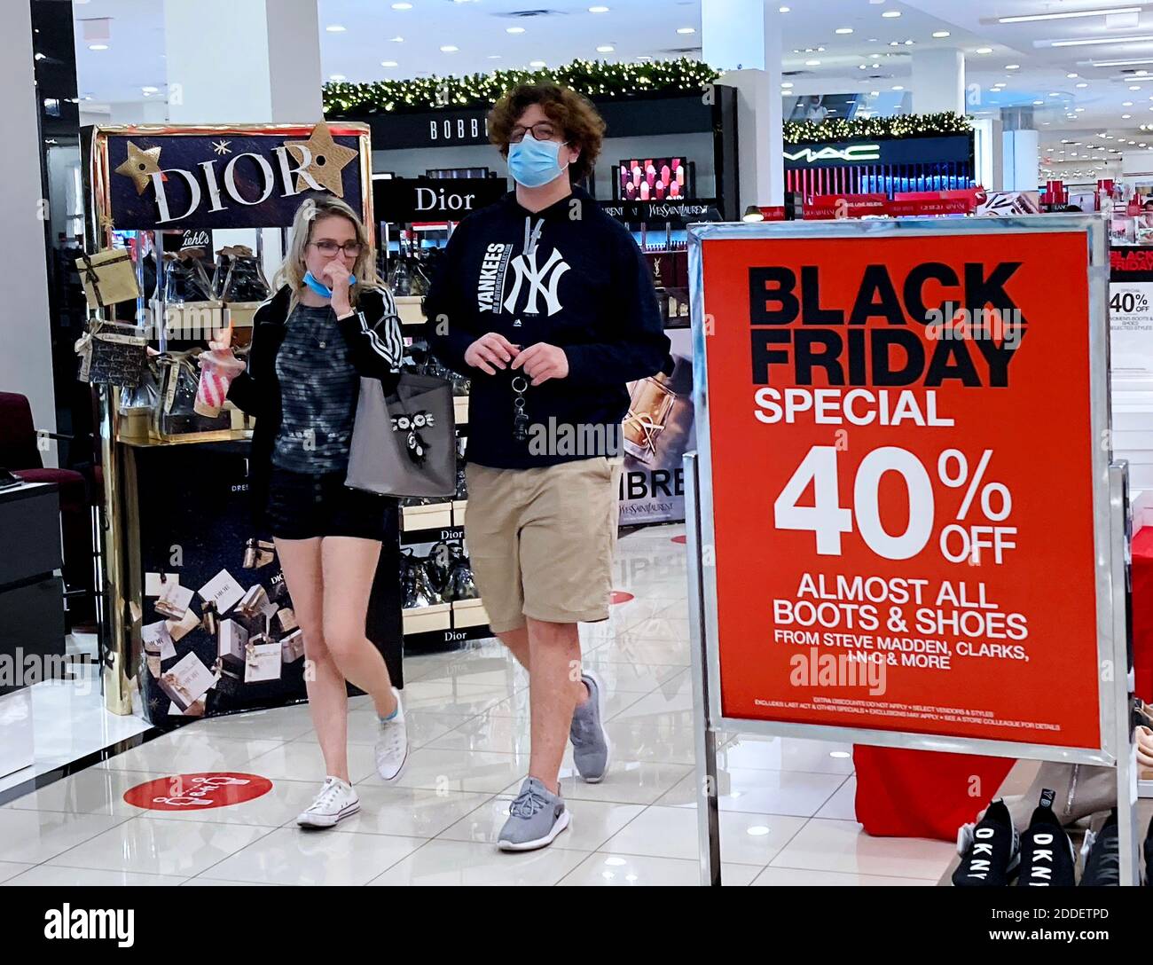 Orlando, United States. 24th Nov, 2020. Shoppers wearing face masks walk  past a Black Friday sale sign in a store at The Mall at Millenia as  merchants prepare for one of the