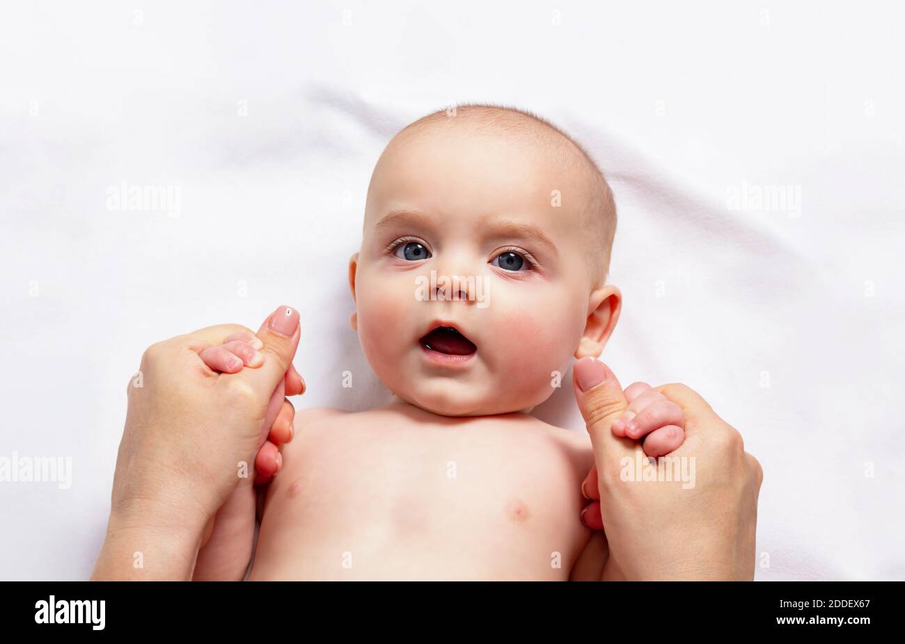 Mum is making hand massage caucasian child up to one year. Gymnastics for small kids. Close up. Top view. Stock Photo