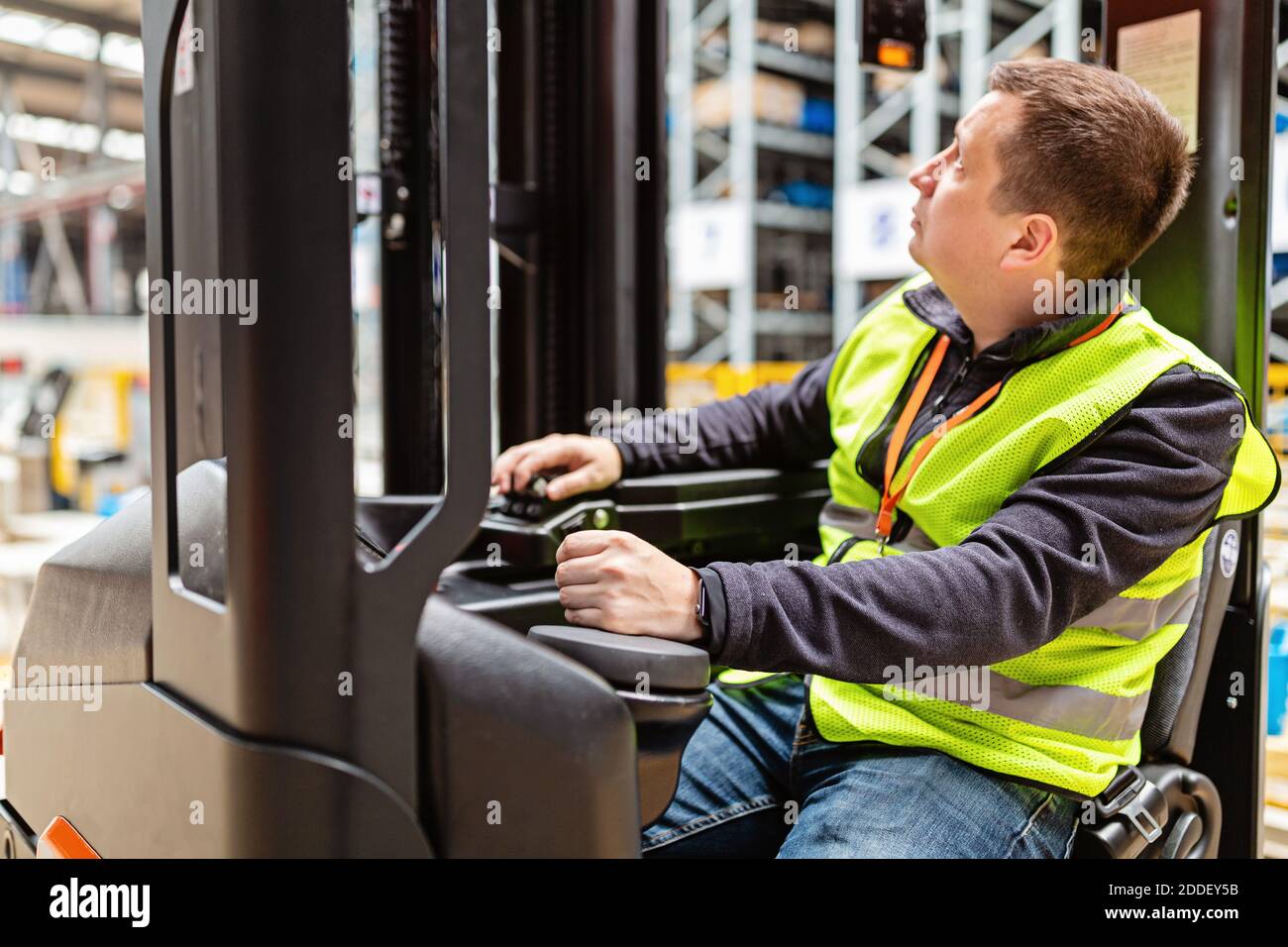 Storehouse employee in uniform working on reachtruck in modern