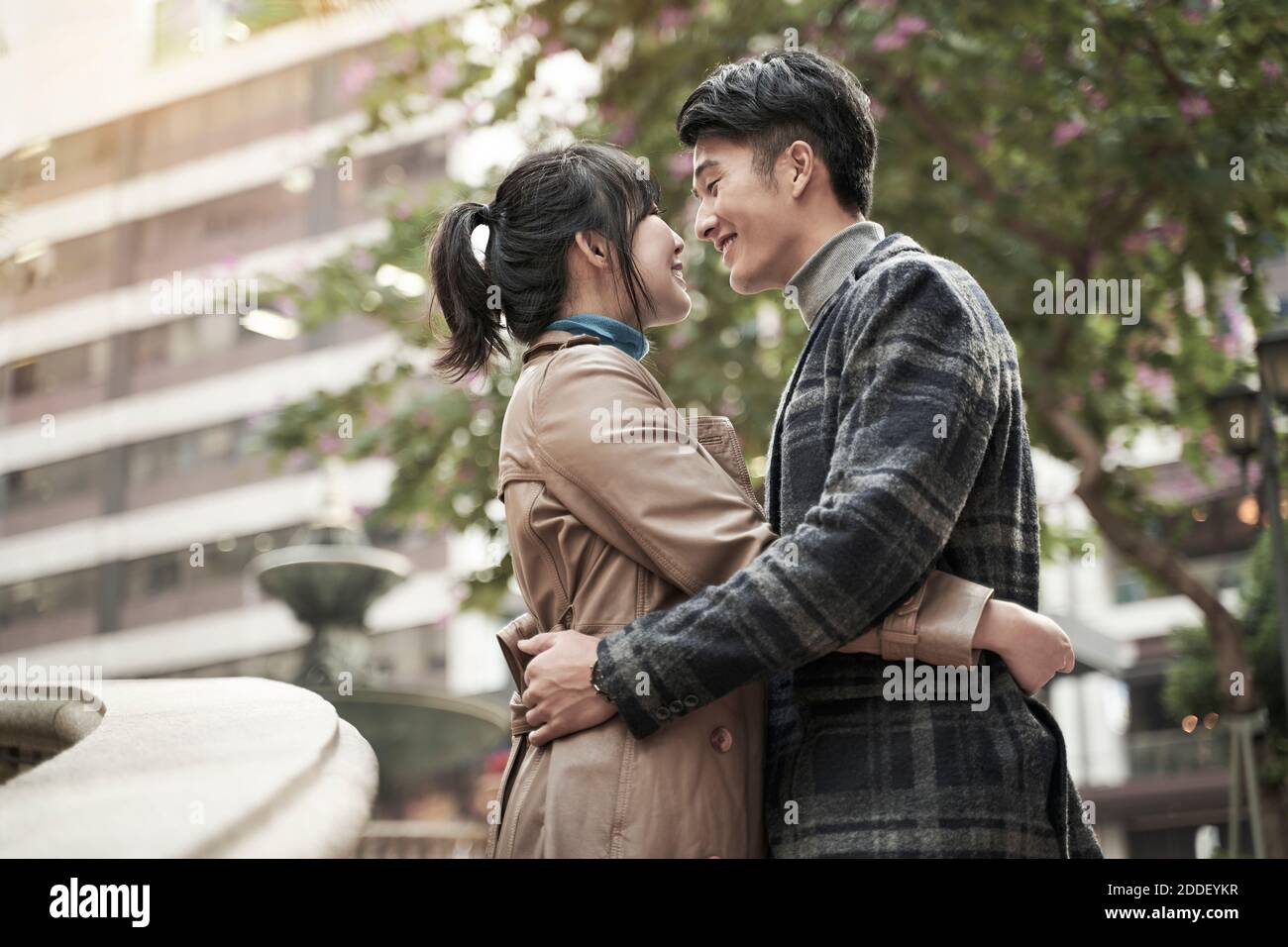 happy young asian couple embracing hugging outdoors Stock Photo
