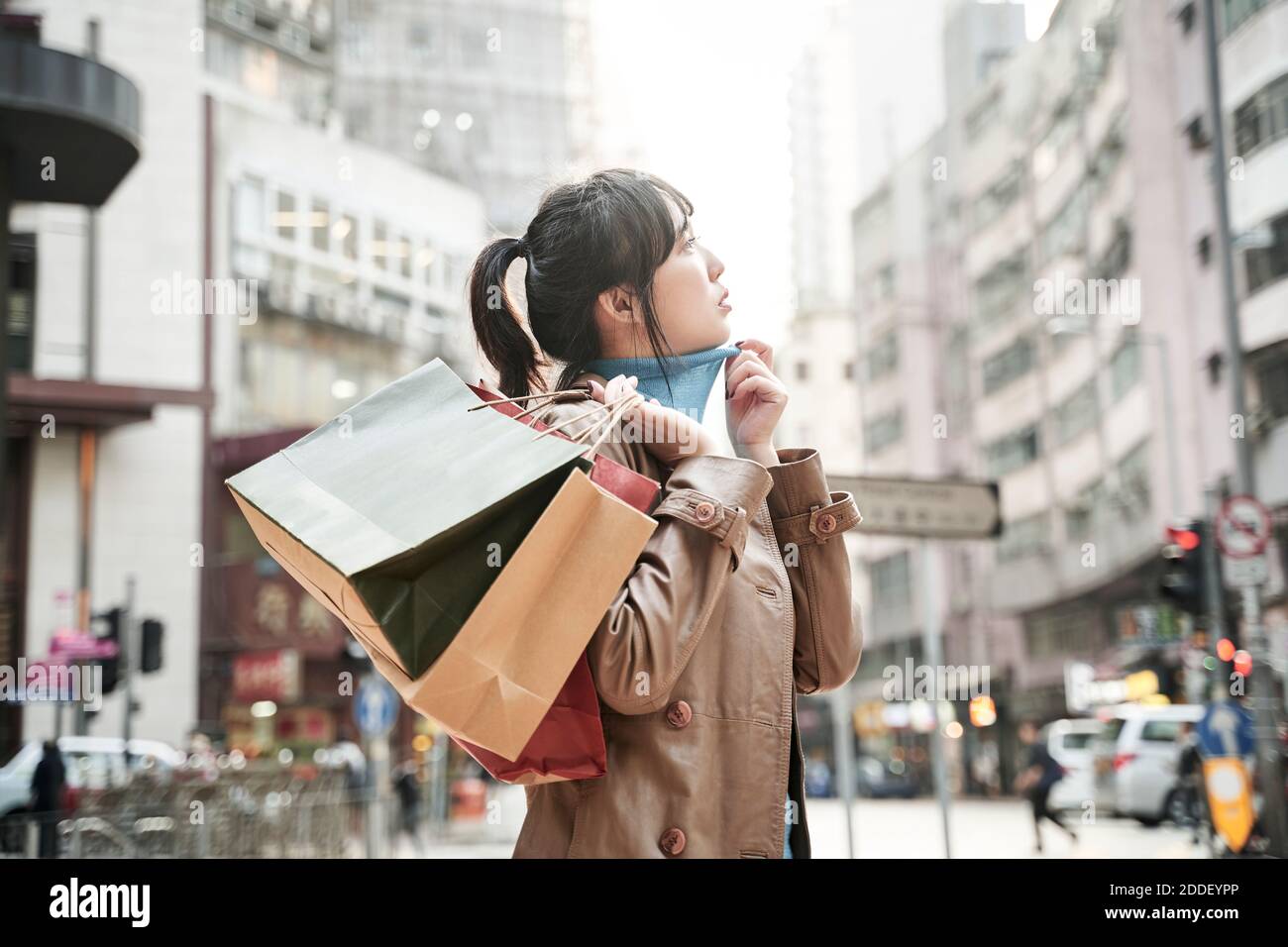 young asian woman carrying shopping bags walking on city street Stock Photo