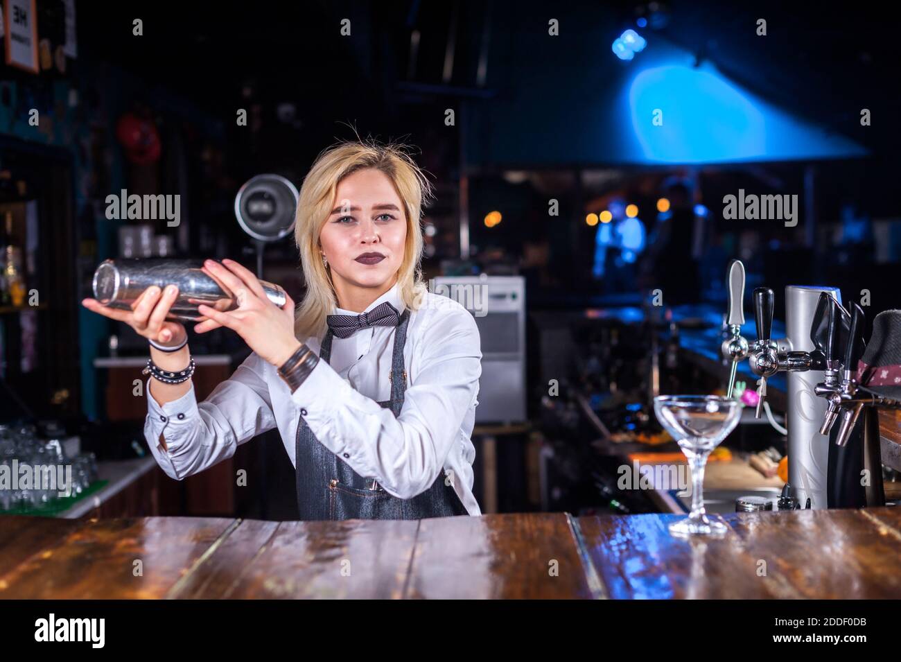 Pretty girl bartending places the finishing touches on a drink behind