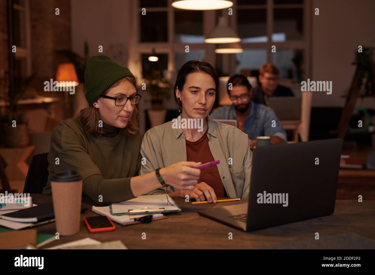 Two designers sitting at the table and using laptop at work they working in team at office Stock Photo