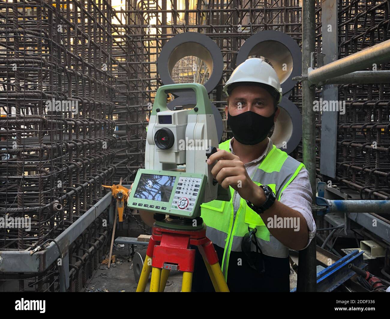 Land surveyor dressed in hardhat,mask and protective vest works on total station Stock Photo Alamy