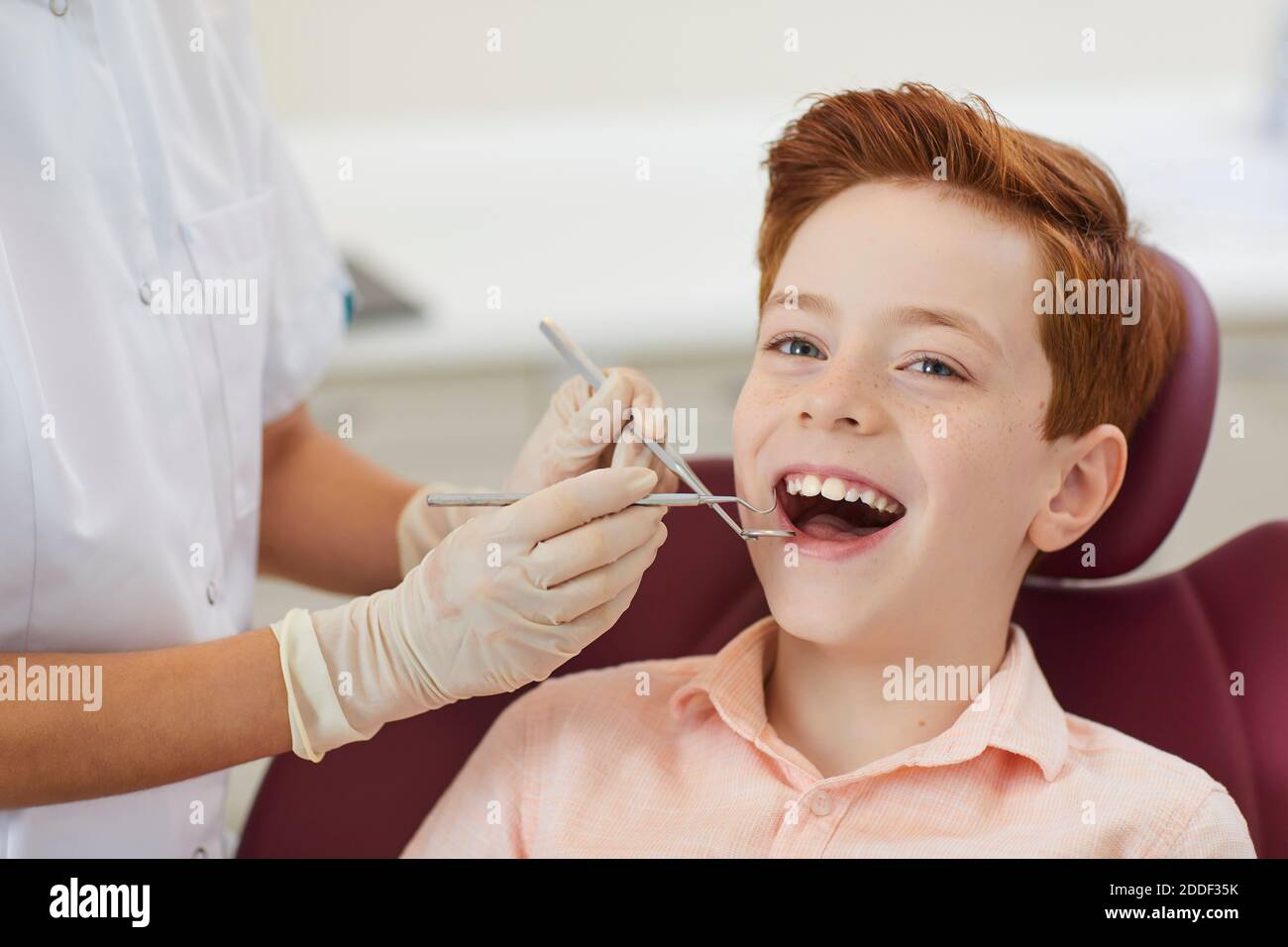 Dental clinic. Smiling boy getting examination of teeth from woman dentist Stock Photo