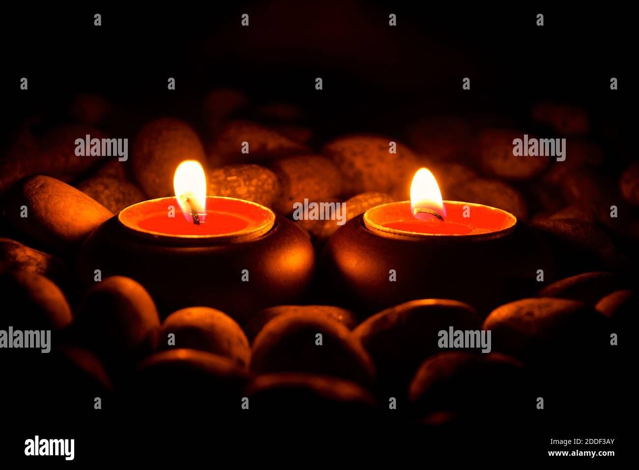 Side view of two burning tealight candles isolated against a warm