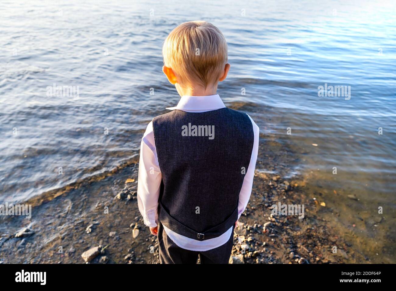 Rear View of Small Boy near the Water outside Stock Photo