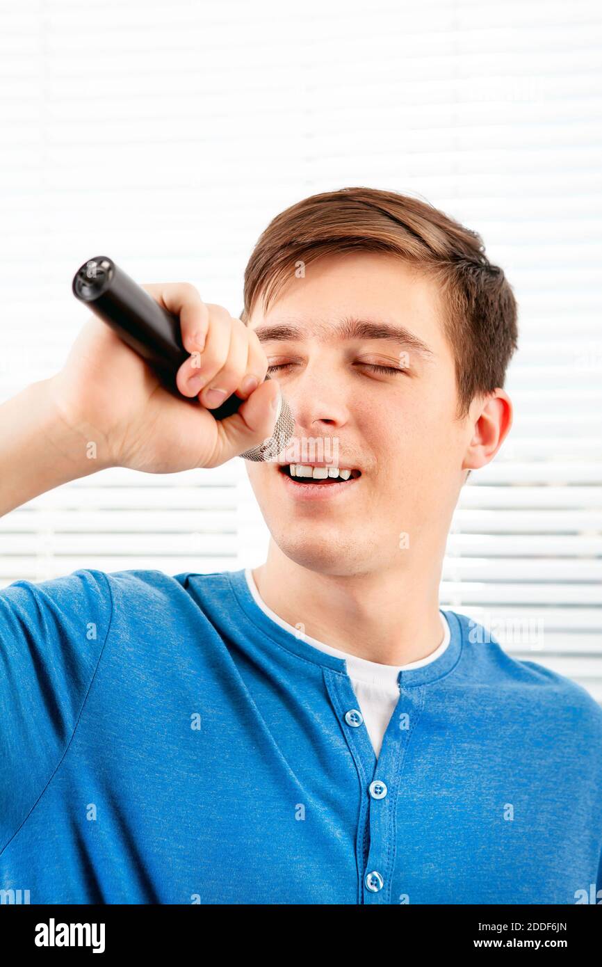 Young Man with a Microphone sing a Song on the Jalousie Background Stock Photo