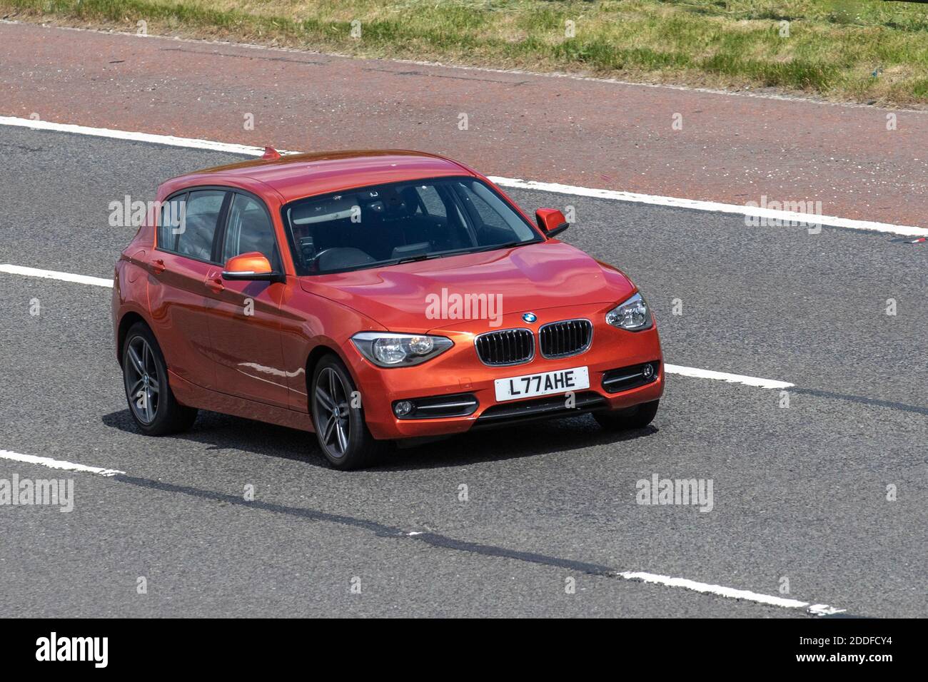 2014 orange BMW 116D Sport; Vehicular traffic, moving vehicles, cars, vehicle driving on UK roads, motors, motoring on the M6 motorway highway UK road network. Stock Photo