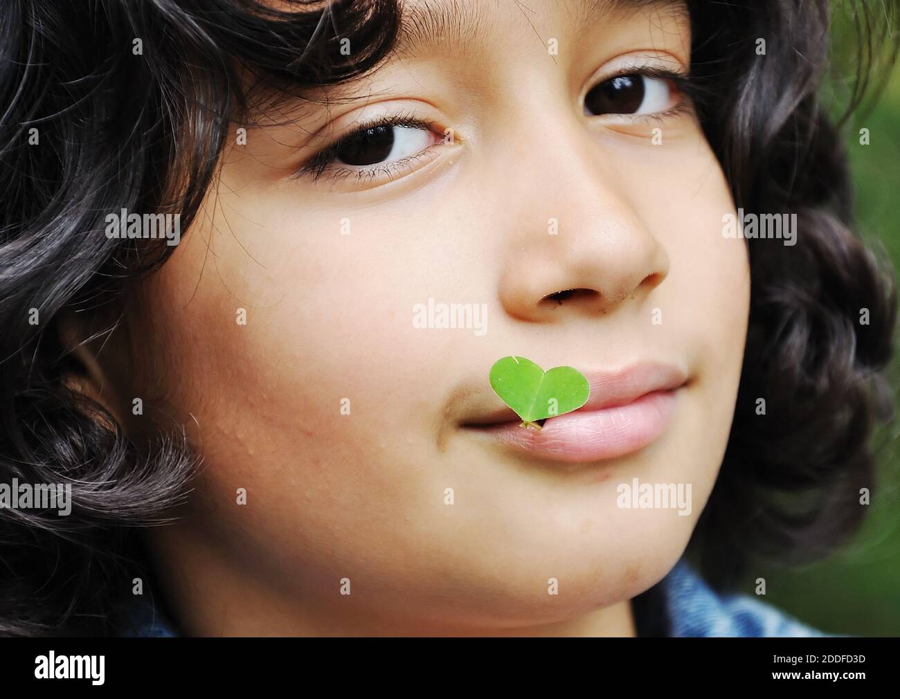 Little cute girl holding plant in natural shape of heart Stock Photo