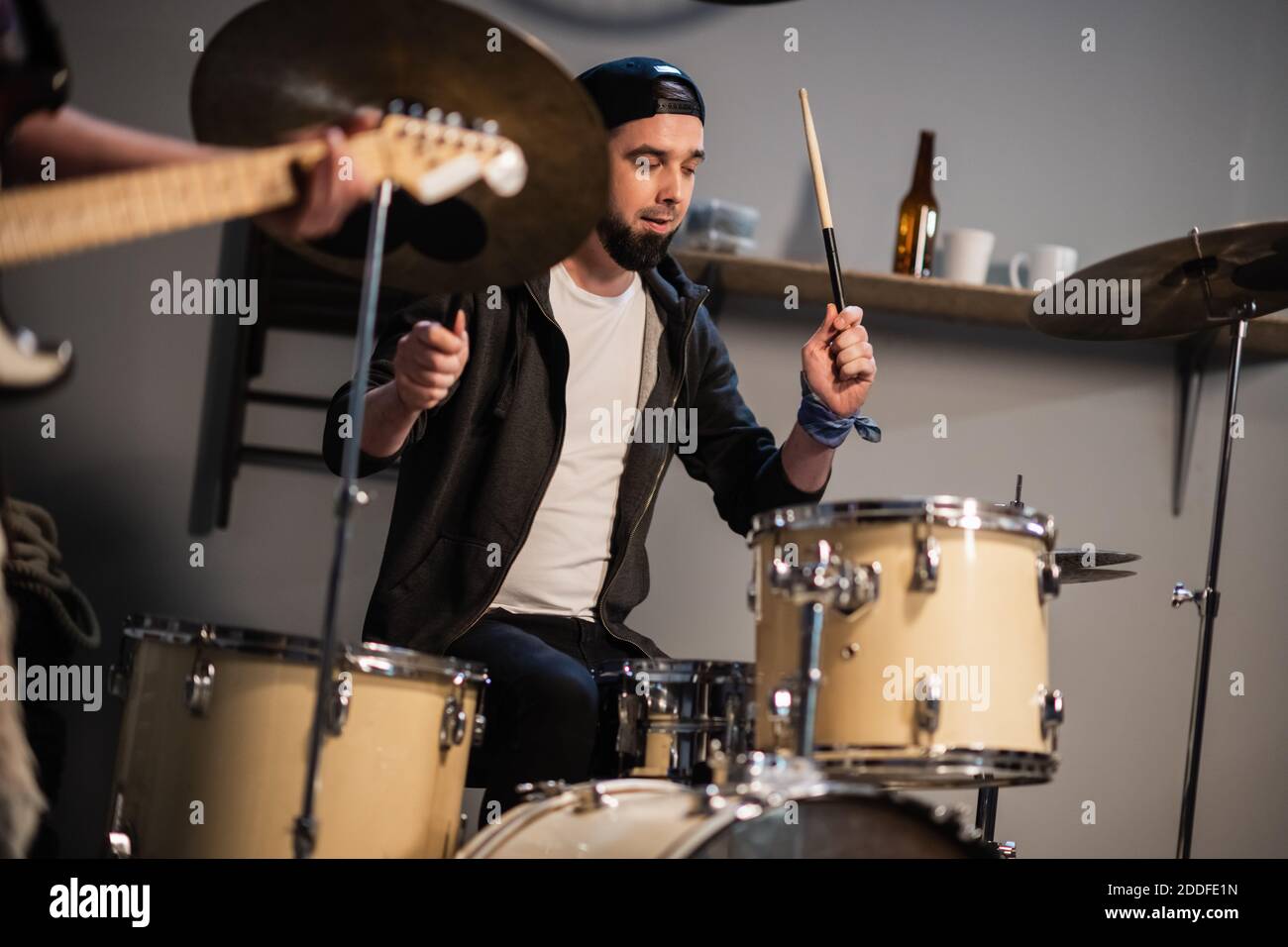 a boysband of guitarist, bassist, and drummer rehearse in their garage Stock Photo