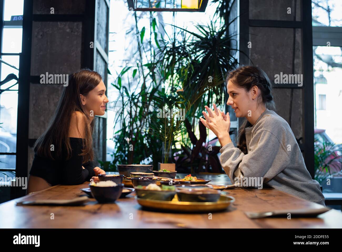 Two girlfriends chatting and having some snacks in a cafe. Stock Photo
