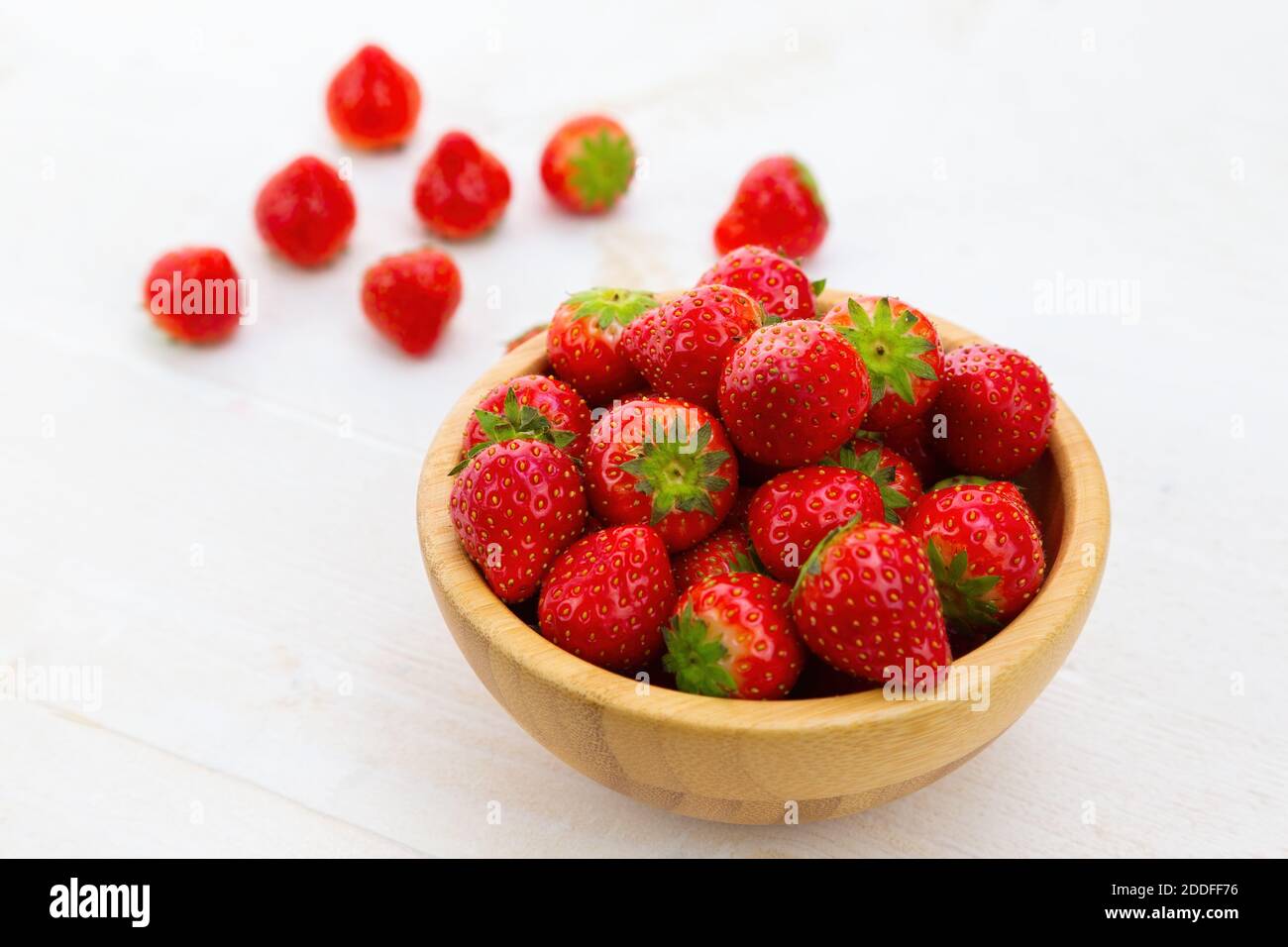 Wooden bowl with fresh strawberries on white desk Stock Photo - Alamy