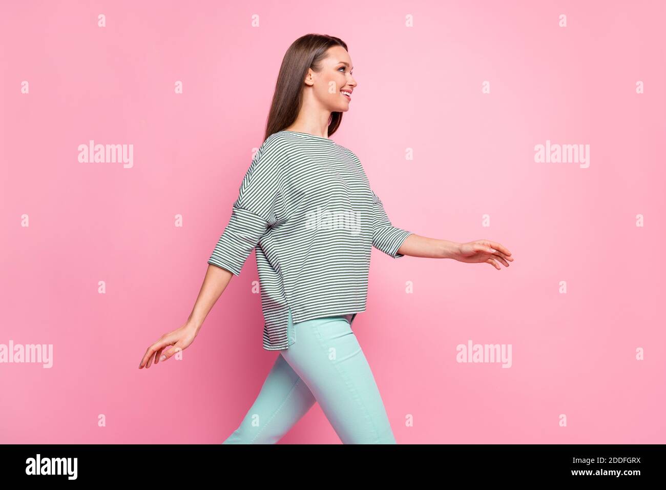 Profile photo of young lady walk wear striped shirt turquoise pants  isolated pastel pink color background Stock Photo - Alamy