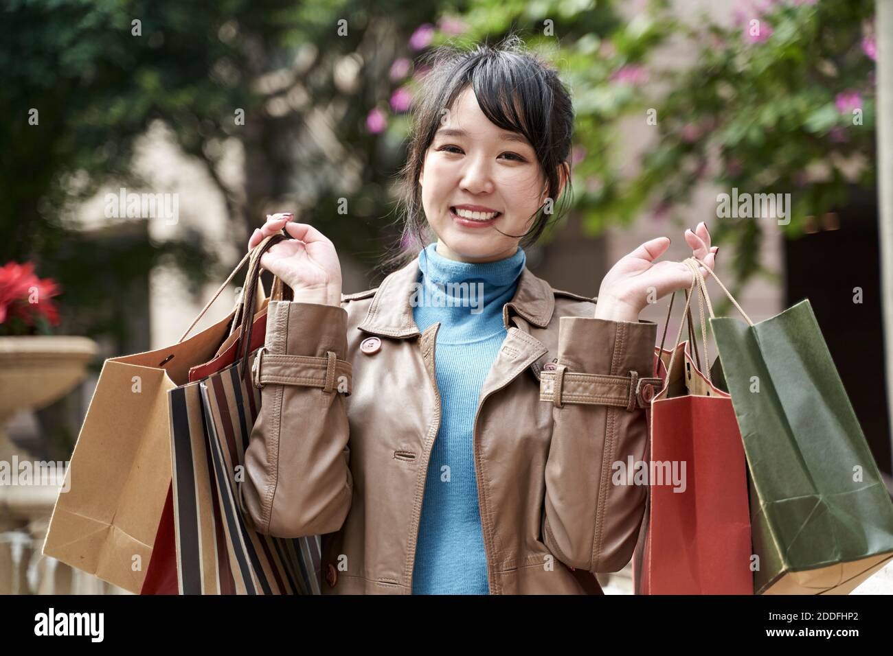 beautiful happy young asian carrying shopping bags looking at camera smiling Stock Photo