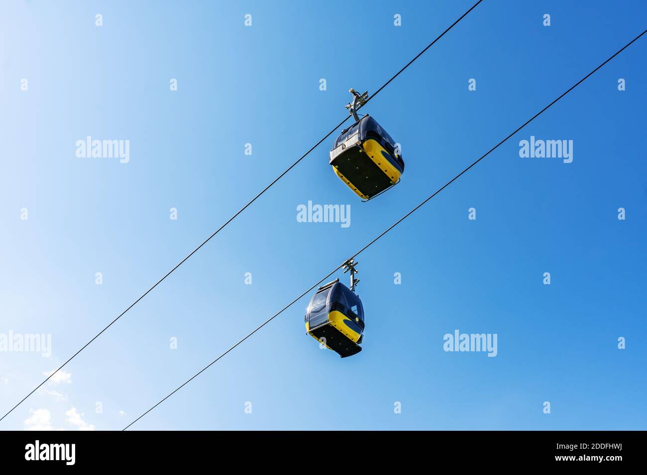 Cable car cabins liftng up on mountain against blue sky Stock Photo - Alamy