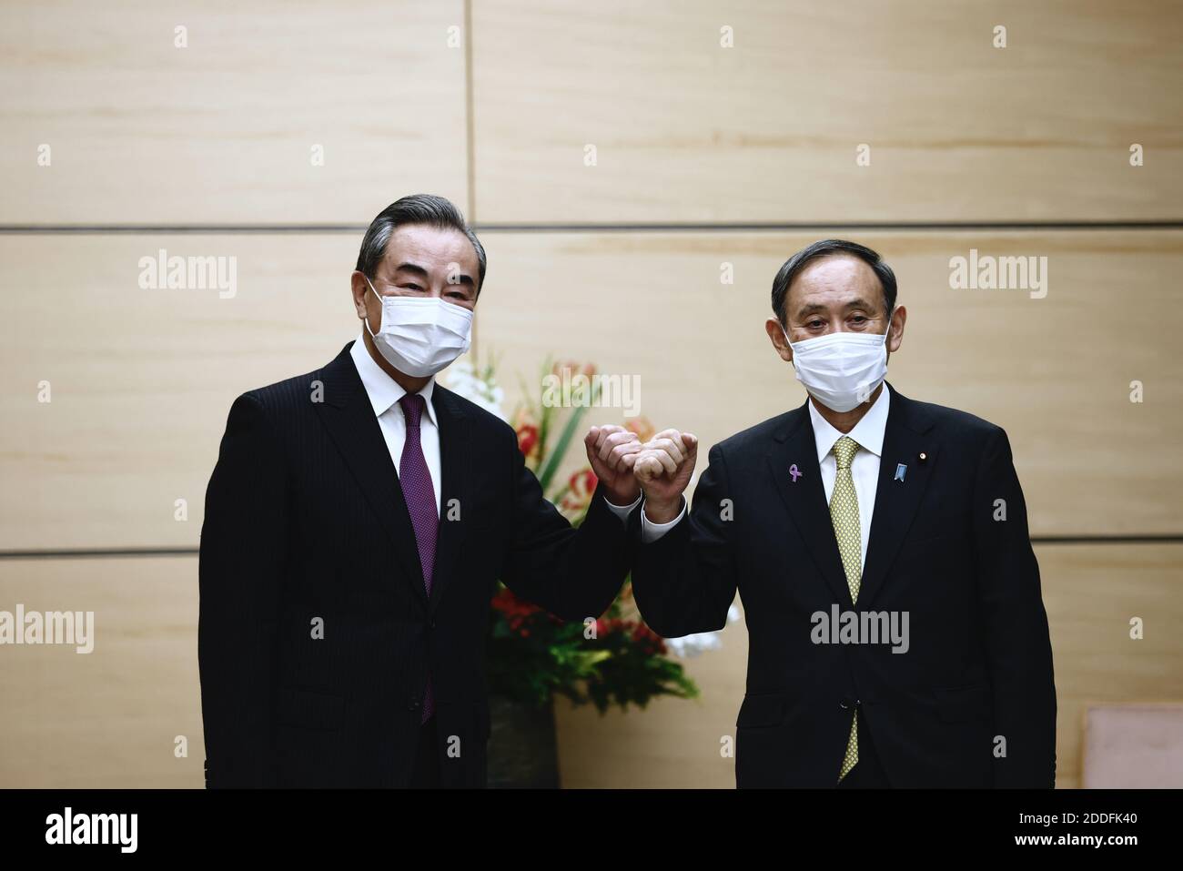 Tokyo, Japan. 25th Nov, 2020. Japan's Prime Minister Yoshihide Suga (R) bumps elbows with China's Foreign Minister Wang Yi (L) at the start of their meeting in Tokyo on November 25, 2020. Credit: POOL/ZUMA Wire/Alamy Live News Stock Photo