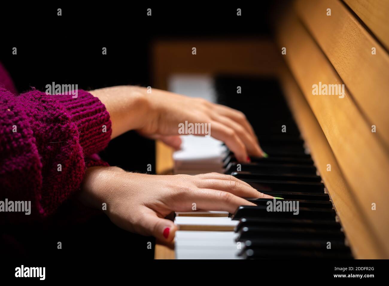 Hands of a girl with colored finger nails playing the piano Stock Photo