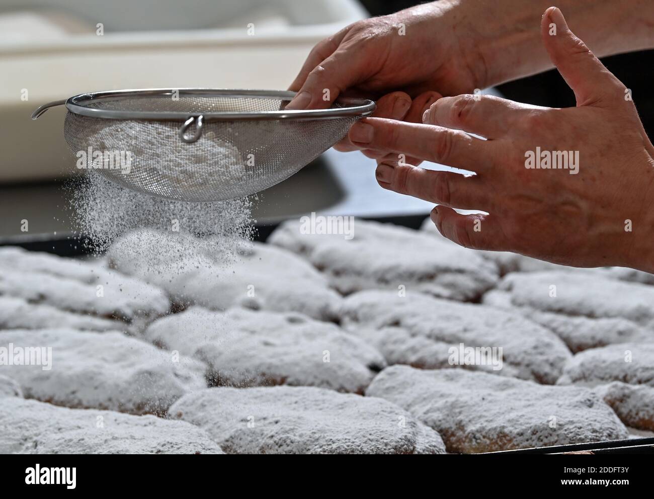 19 November 2020, Saxony-Anhalt, Klosterhäseler: Master baker Rolf Block sugars freshly baked Naumburg Stollen in his bakery in Klosterhäseler. Around 5000 pieces of the traditional Christmas cake leave the bakery this year. The Corona pandemic is also having an effect here, so the café of the bakery and confectionery is currently closed, but the online shop is doing much better. The special feature of his Naumburg Stollen are the dried and kirsch-soaked sweet cherries, which are added to the dough in place of the sultanas. Photo: Hendrik Schmidt/dpa-Zentralbild/ZB Stock Photo