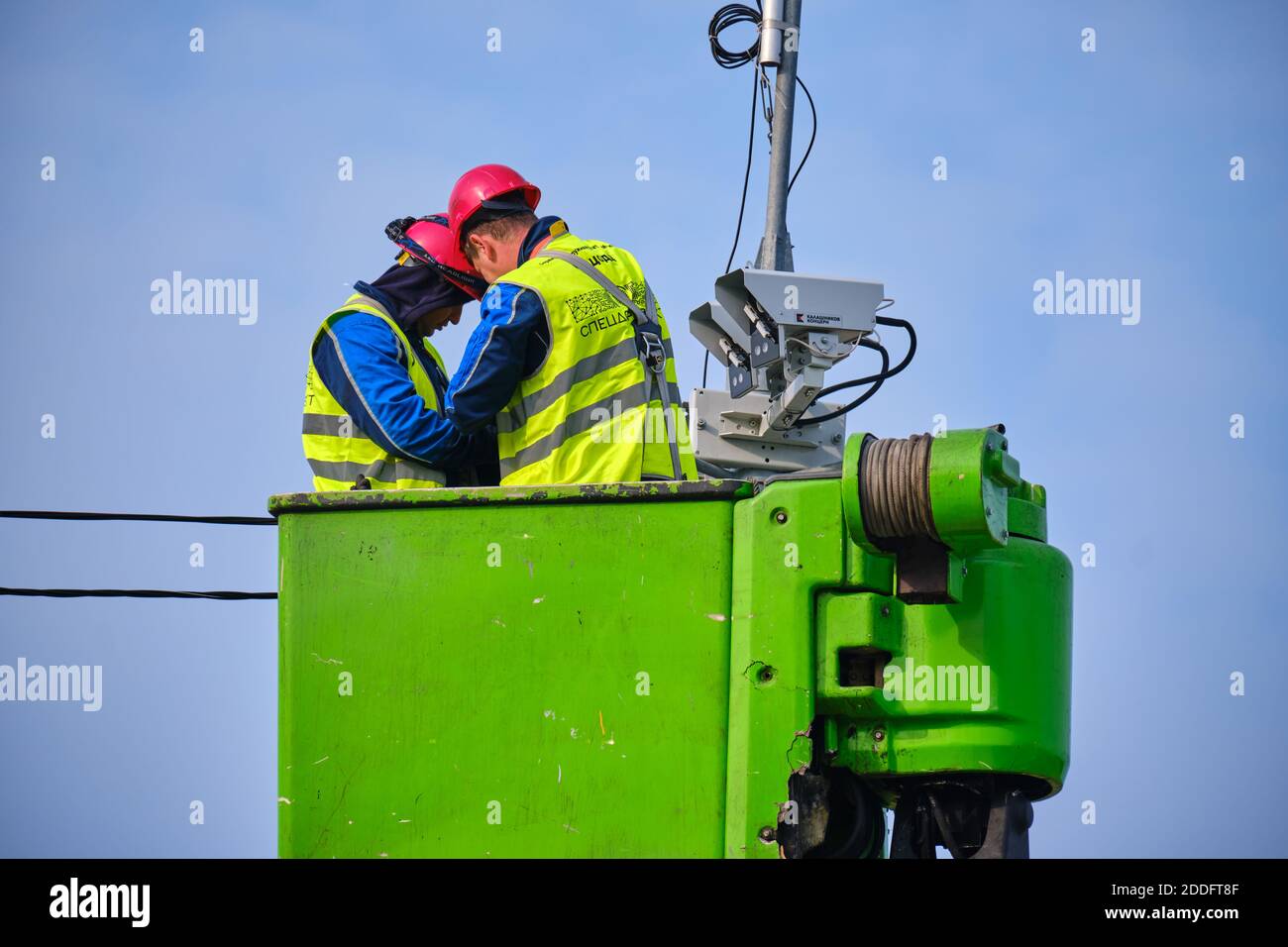 Male engineers repair a road surveillance camera tower while standing ...
