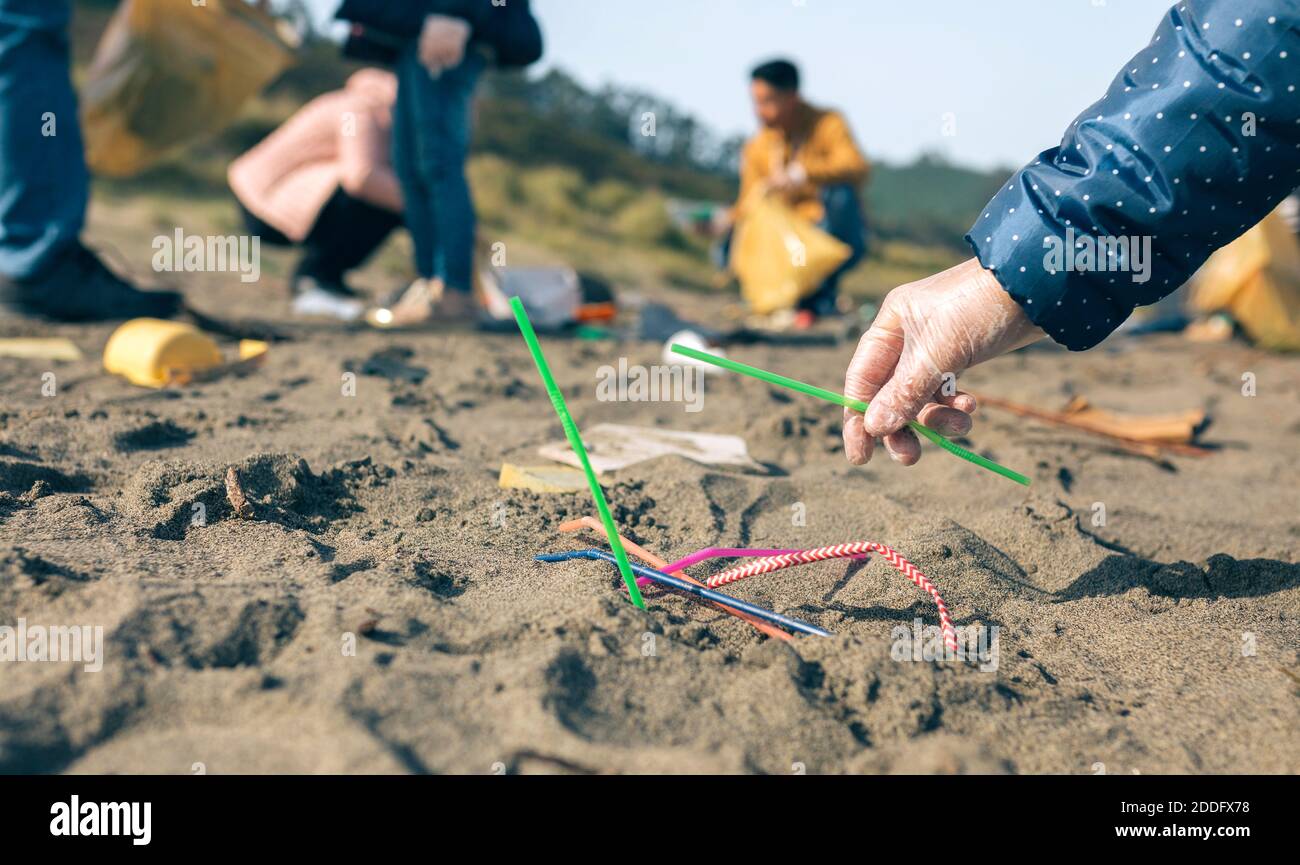 Woman picking up straws on the beach Stock Photo