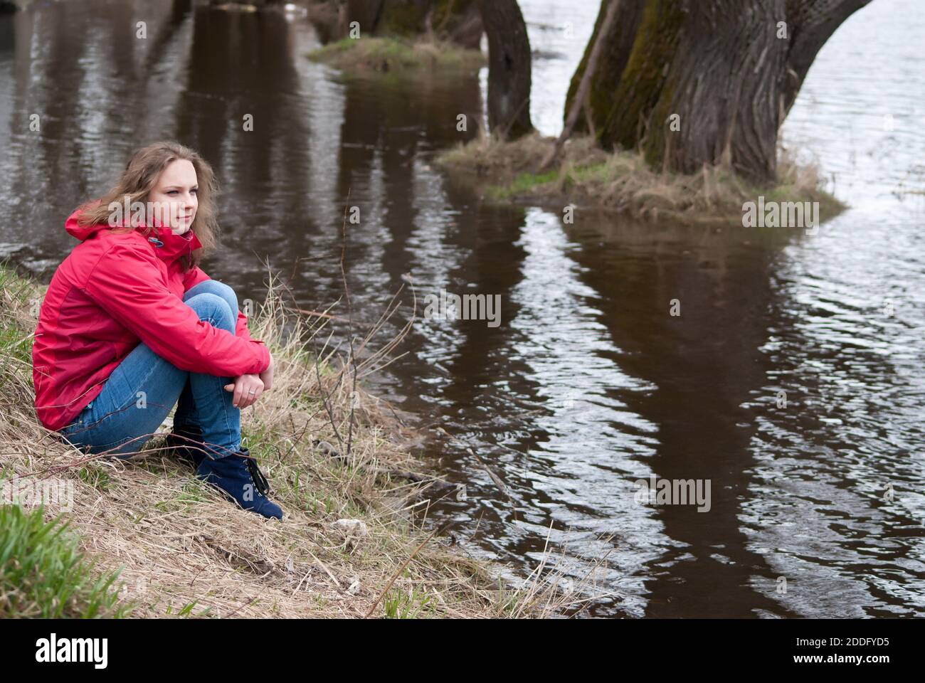The girl sits on the river bank Stock Photo