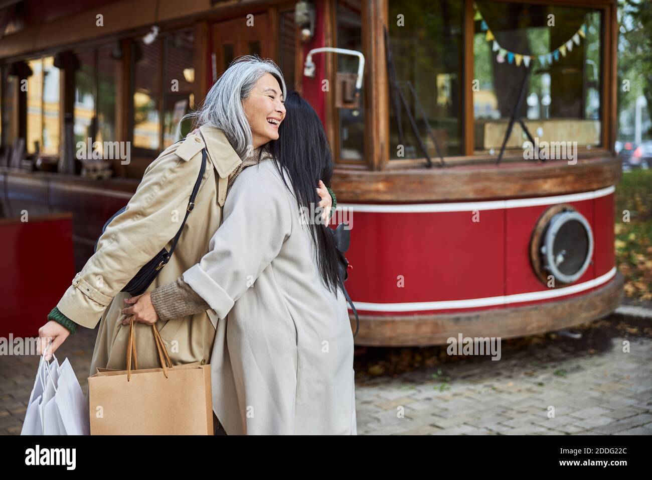 Happy female friends hugging on city street Stock Photo - Alamy