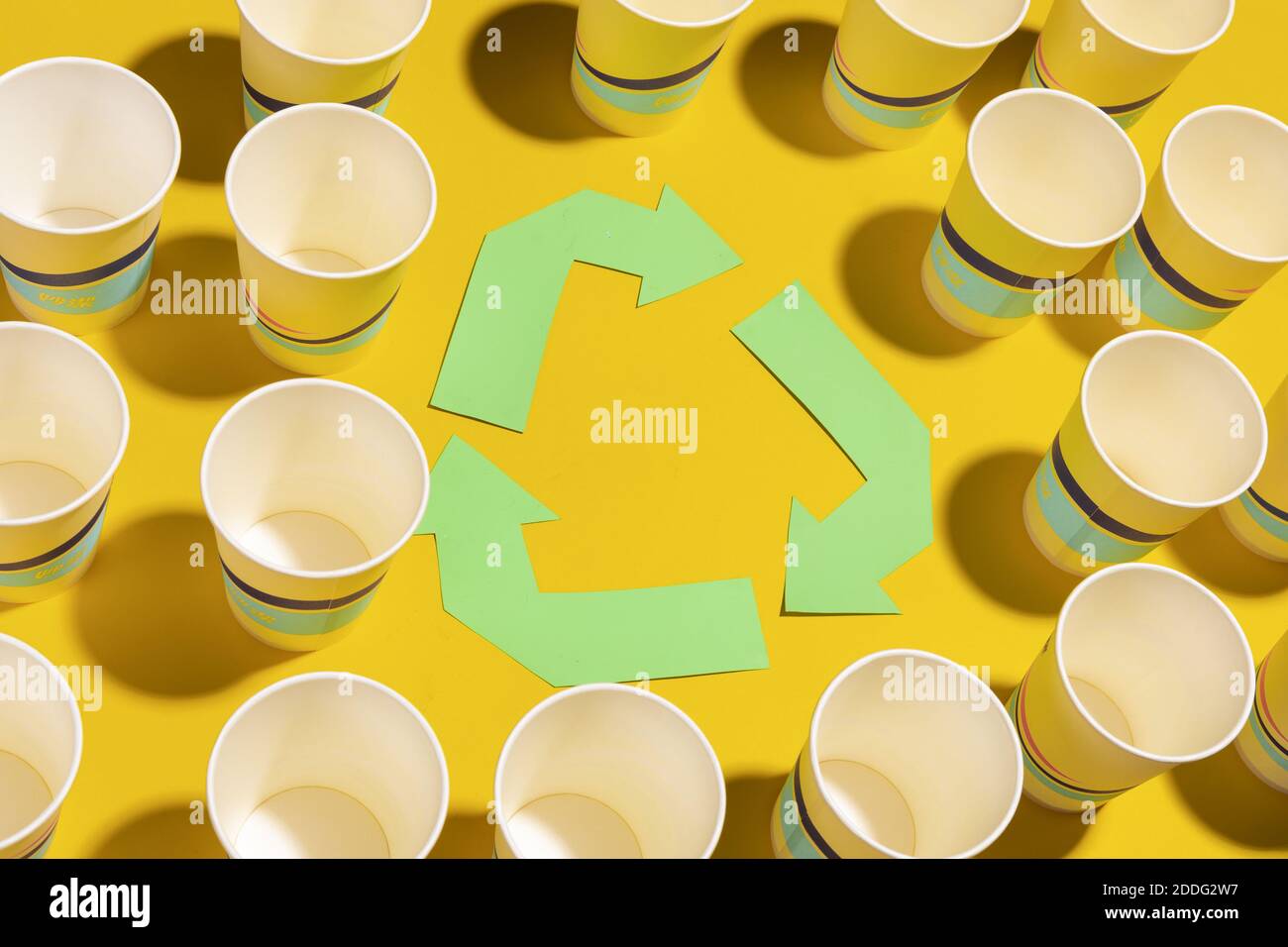 Recycling sign and paper cups on yellow surface Stock Photo - Alamy