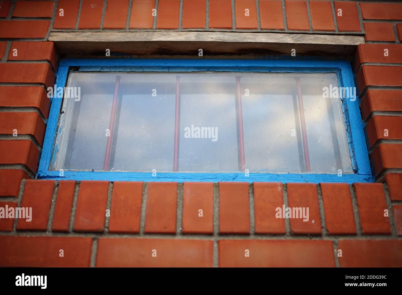 Low window with blue frame and iron grating in a brick building Stock Photo