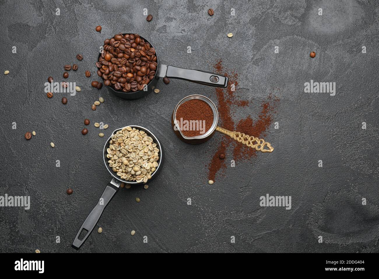 Green and roasted coffee beans with powder on dark background Stock Photo